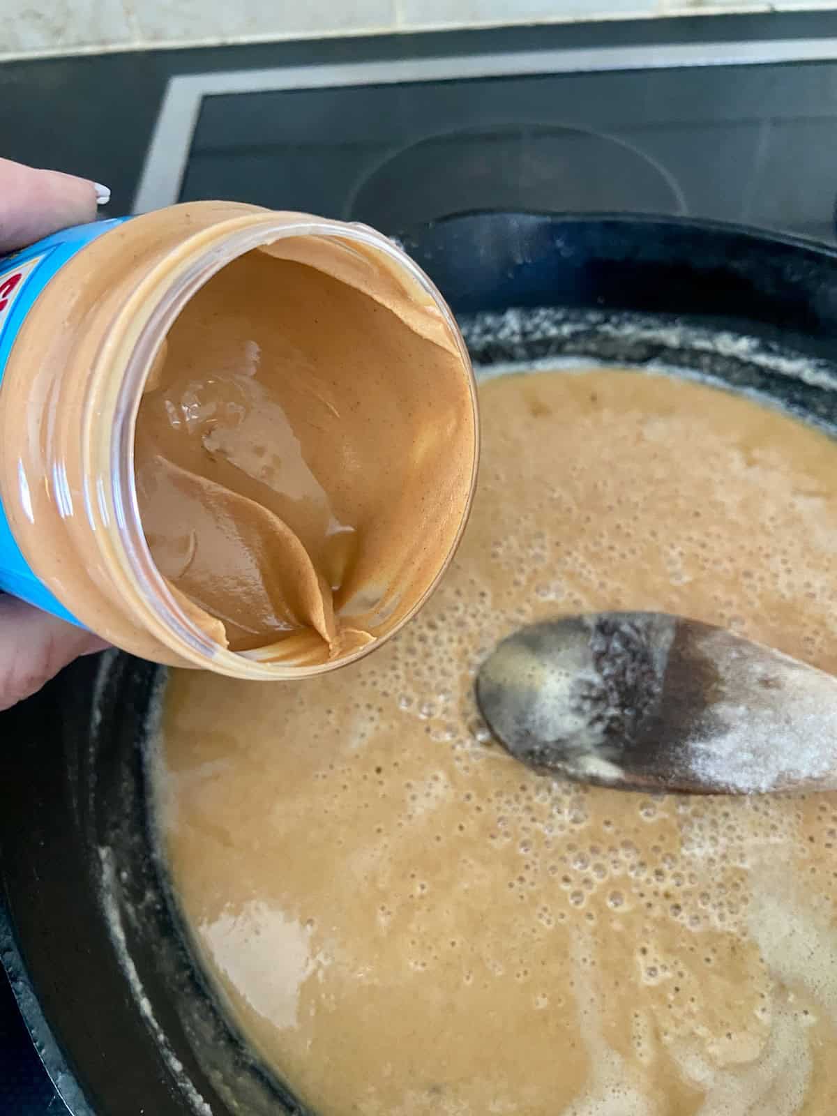 Jar of peanut butter next to a skillet with roux.