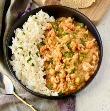 White rice and crawfish etouffee in black bowl.