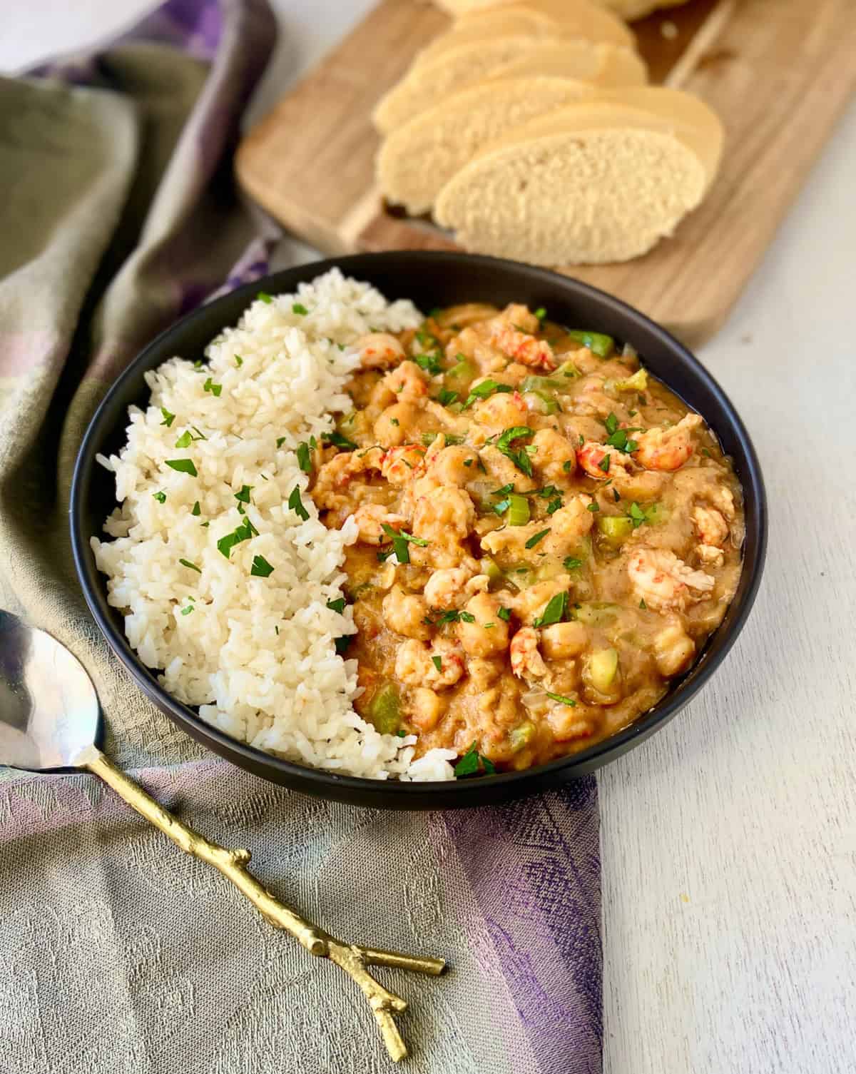 Crawfish etouffee and white rice in a black bowl.