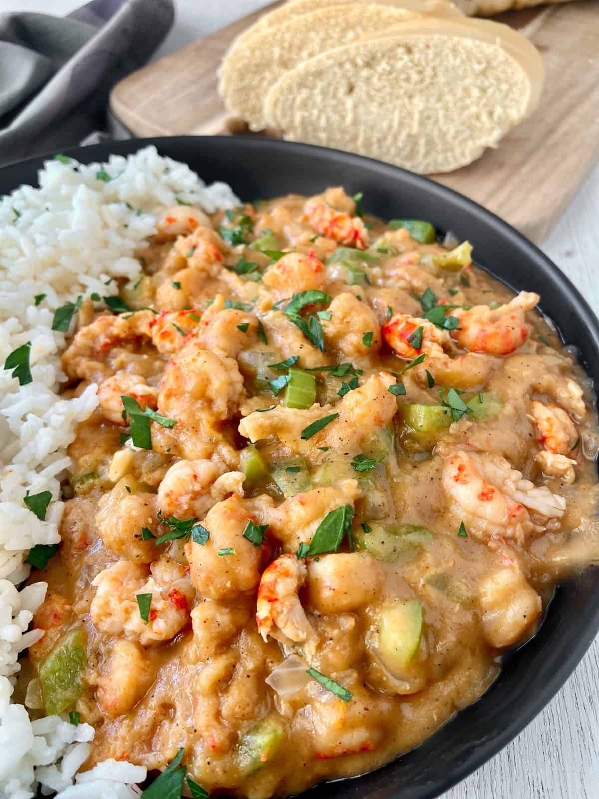 Close up image of crawfish etouffee and rice in black bowl.