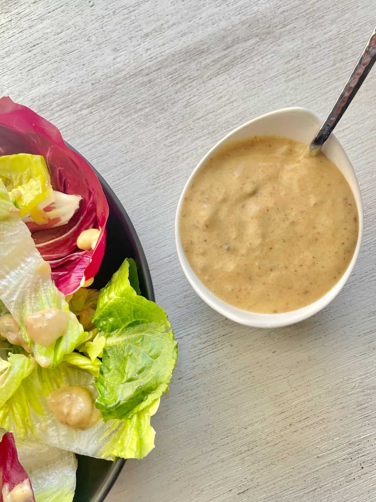 Medjool date vinaigrette in white serving bowl with spoon.