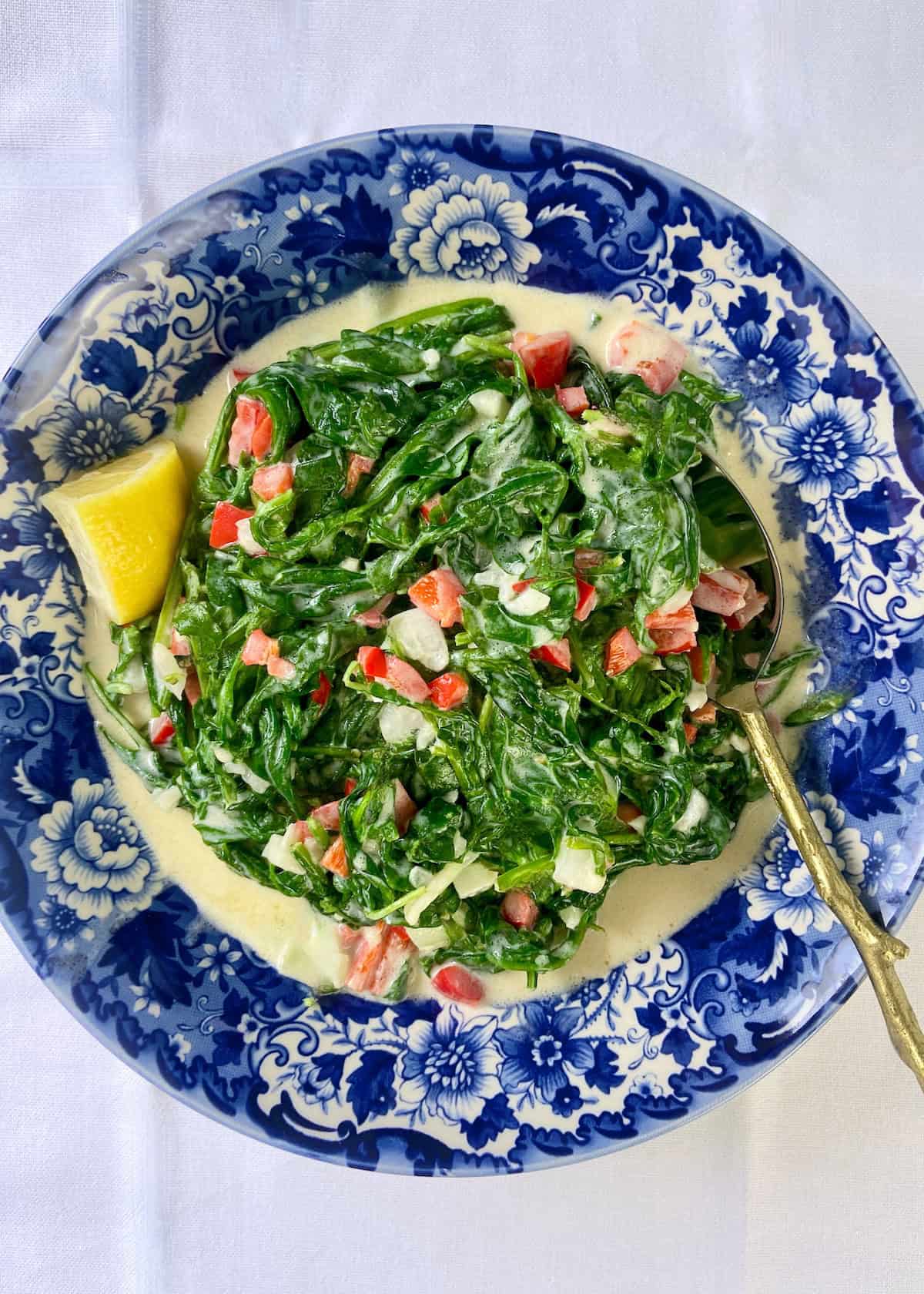 Mediterranean style Creamed Spinach and arugula in a decorative blue bowl.