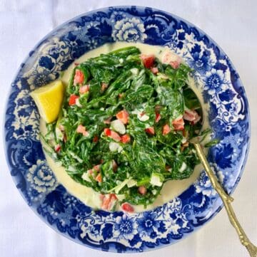 Mediterranean style creamed spinach and arugla in a decorative blue bowl.