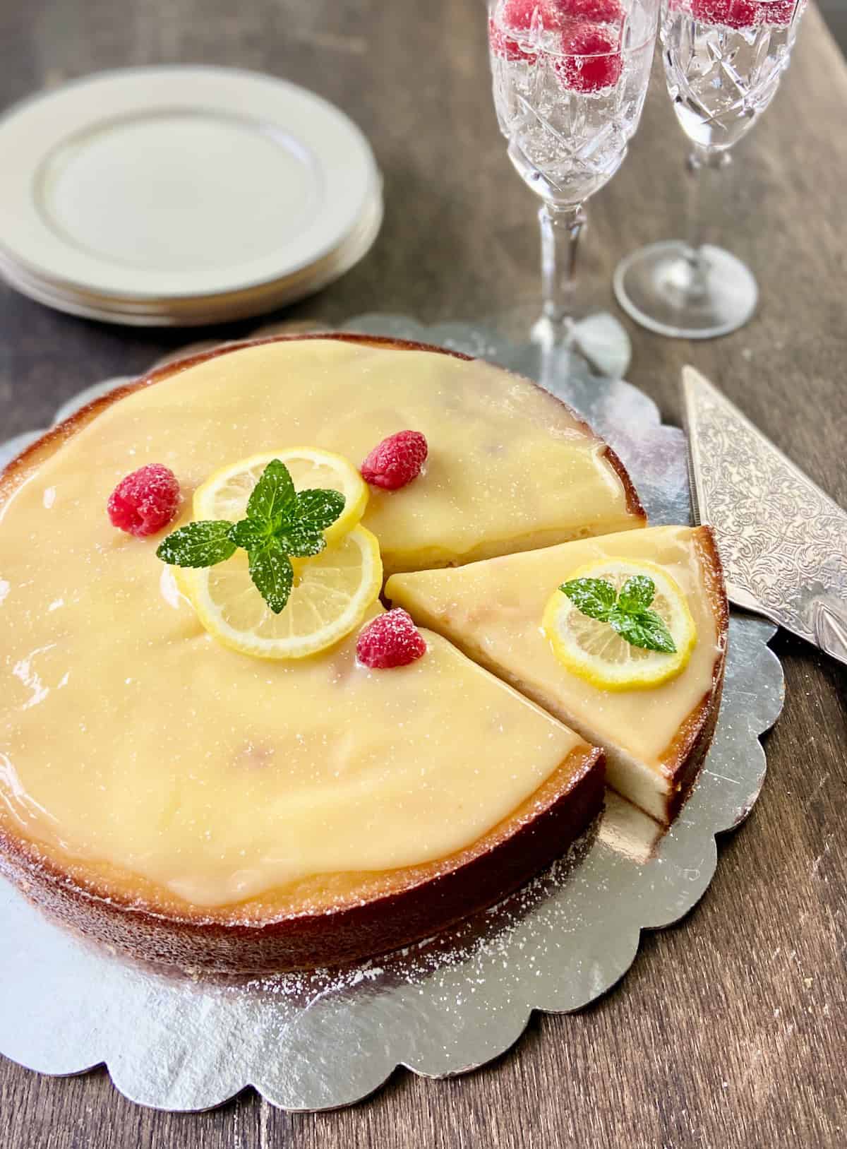 Lemon Ricotta Cake garnished with lemon slices, raspberries and a sprig of mint.