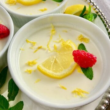 Lemon Panna Cotta in ramekin garnished with sliced lemon, a raspberry and a sprig of mint.