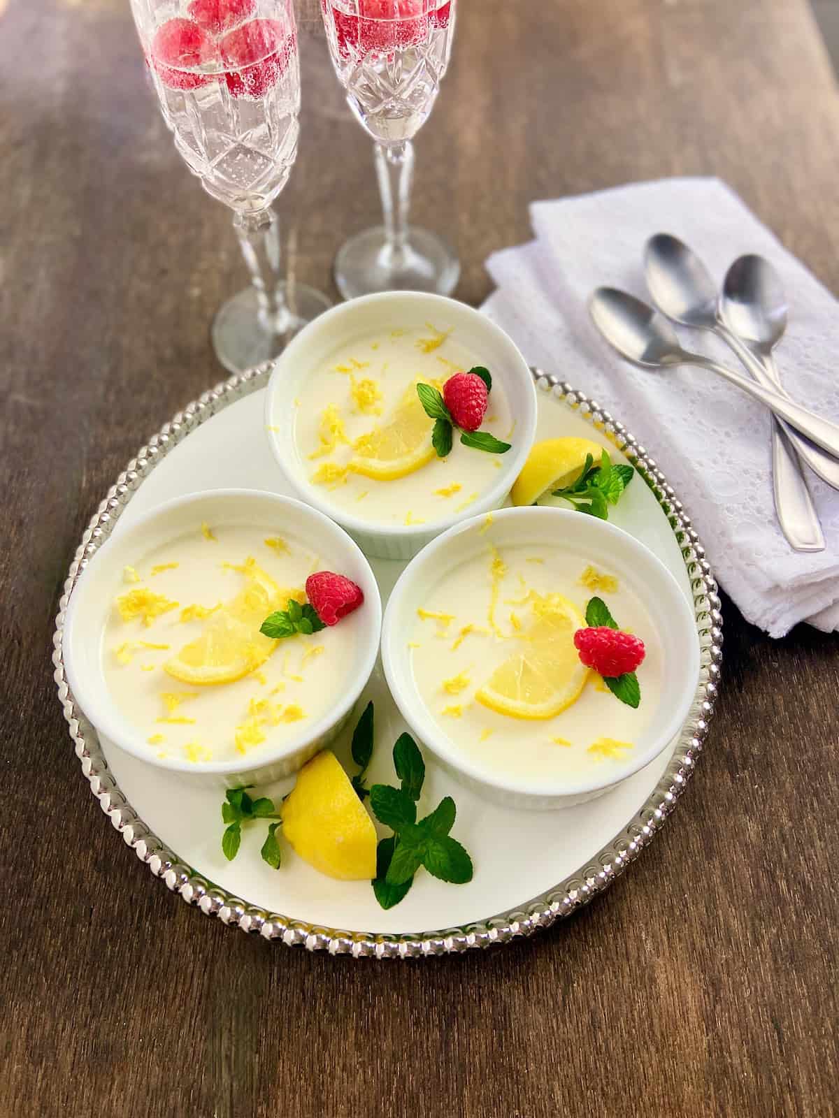 Silver beaded tray with three ramekins of Lemon Panna Cotta garnished with sprigs of mint.