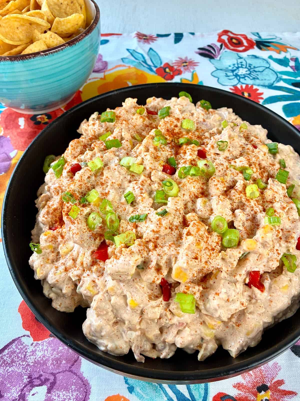 Corn Dip in black bowl garnished with chives and paprika.
