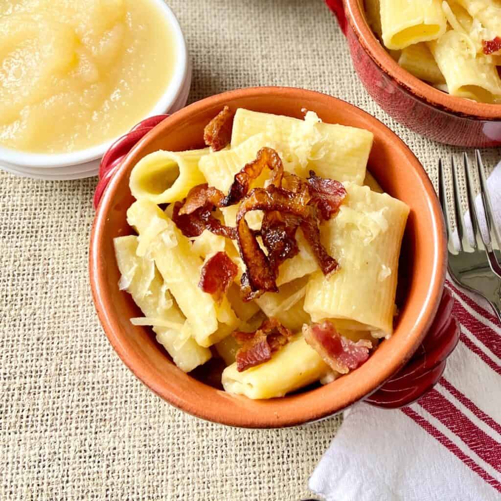 Alpine macaroni in a red bowl with a side of applesauce.