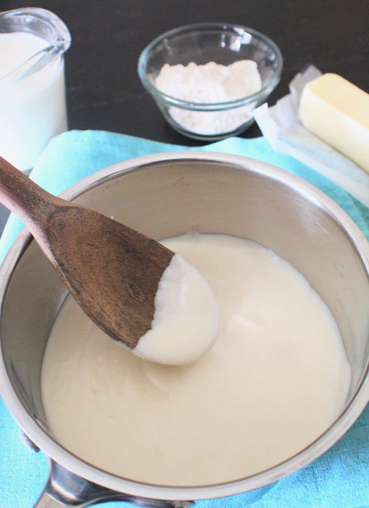 White cream sauce on wooden spoon.