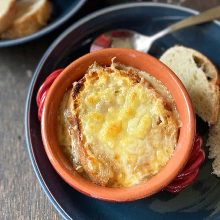 French onion soup in red bowl.
