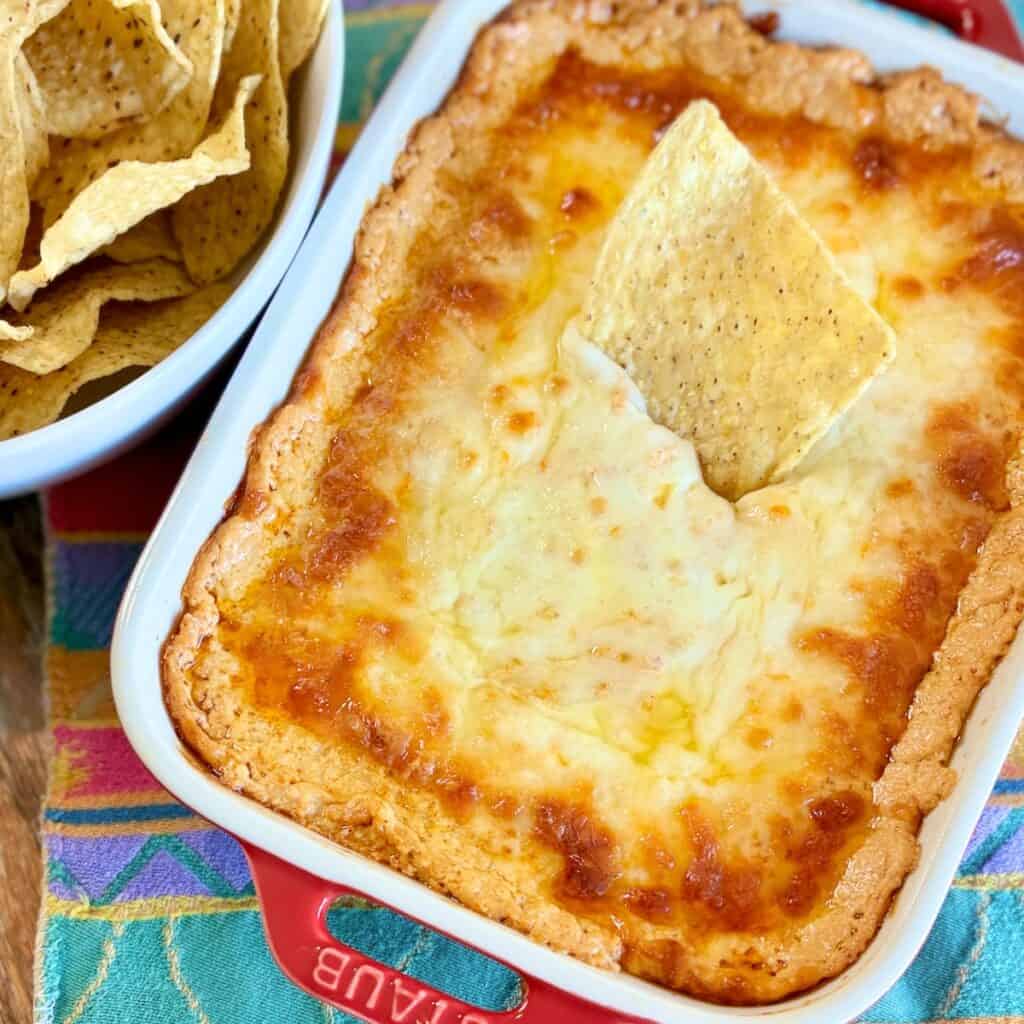 Baked enchilada dip in red casserole dish.