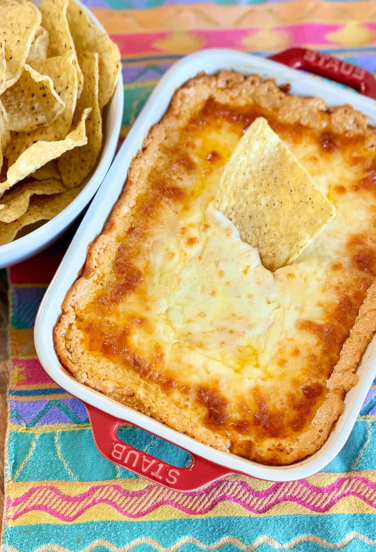 Baked Enchilada Dip in red baking dish topped with a corn tortilla.
