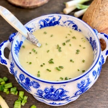 Vichyssoise Creamy Potato Leek soup in decorative tureen garnished with minced chives.