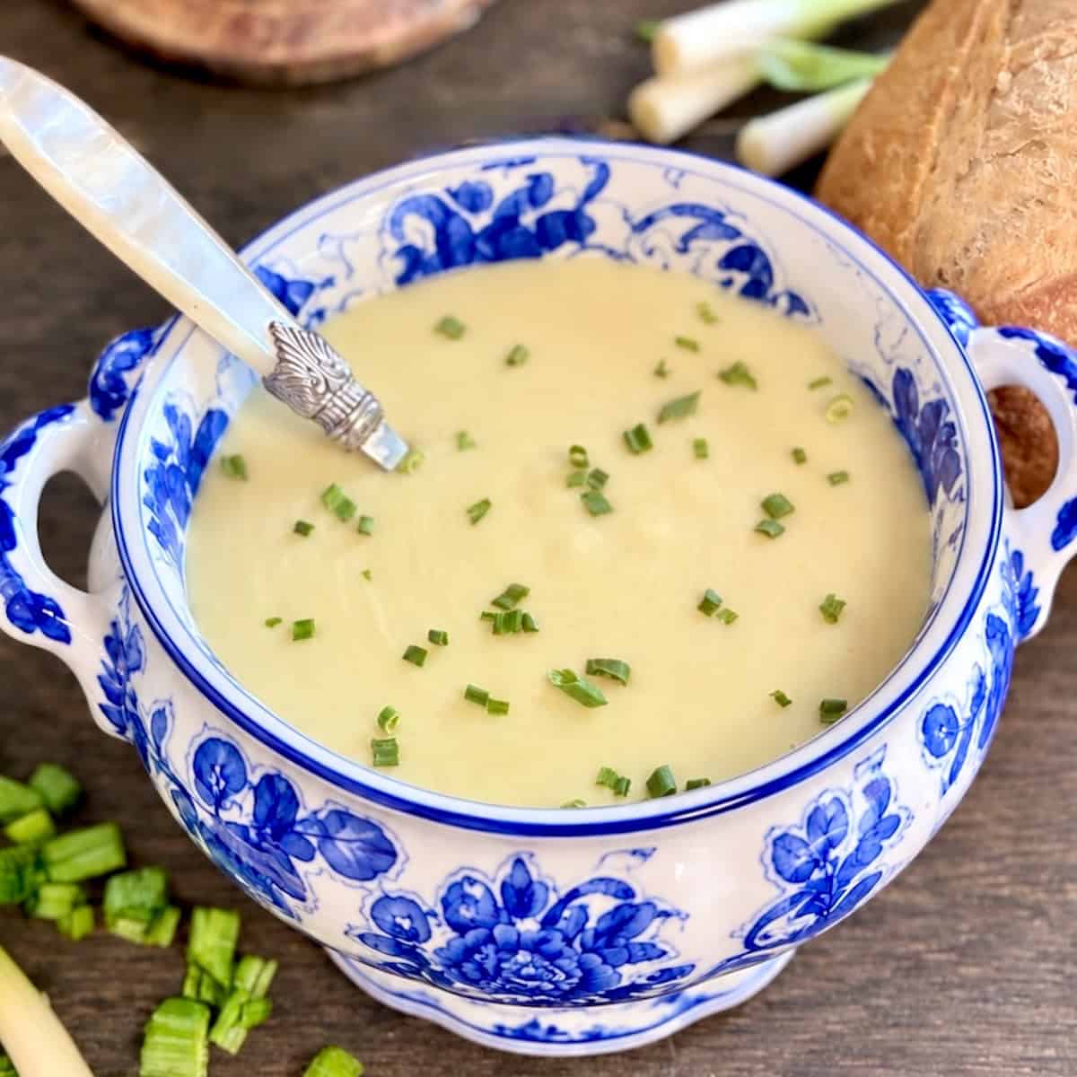 Vichyssoise Creamy Potato Leek soup in decorative tureen garnished with minced chives.