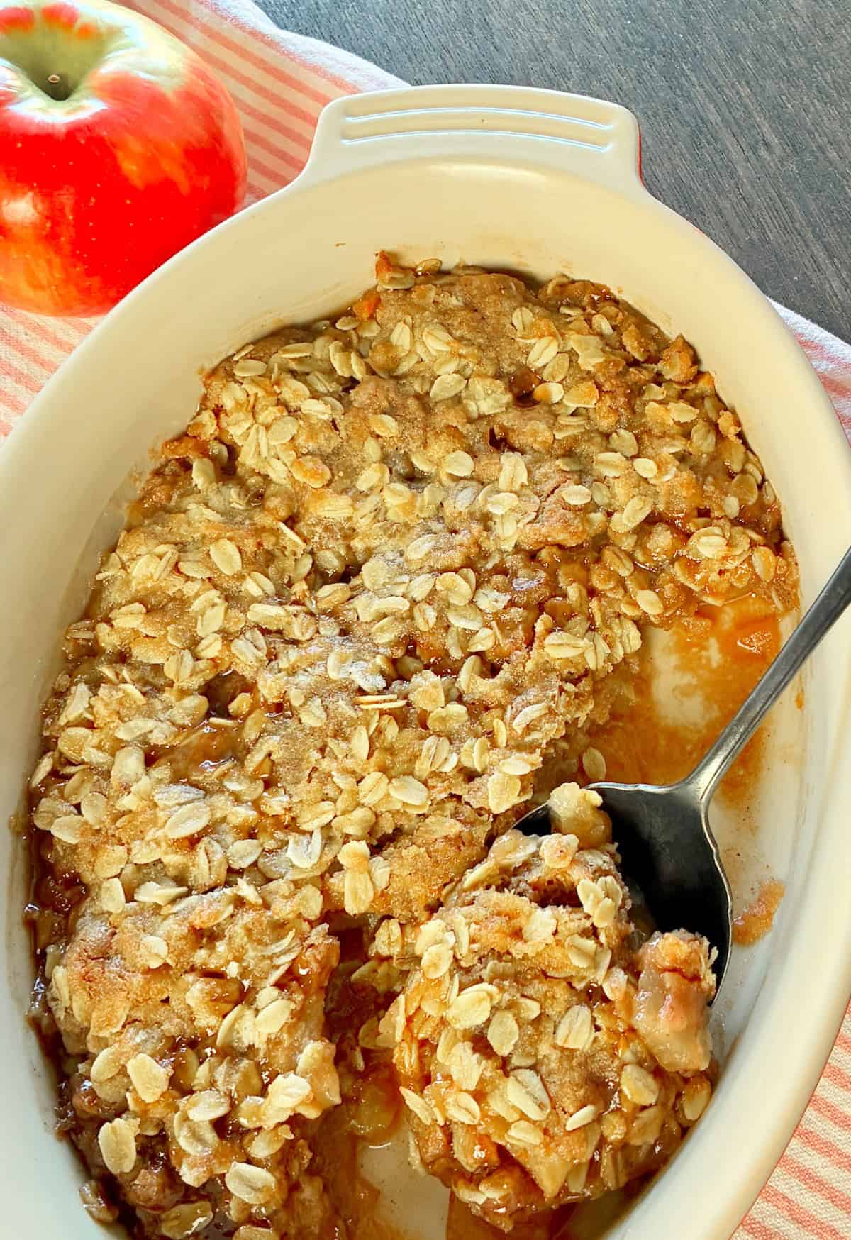 Apple crisp in ovel baking dish with antique serving spoon.