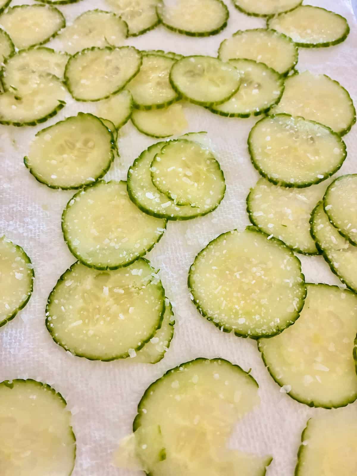 Salted cucumber slices on paper towel.
