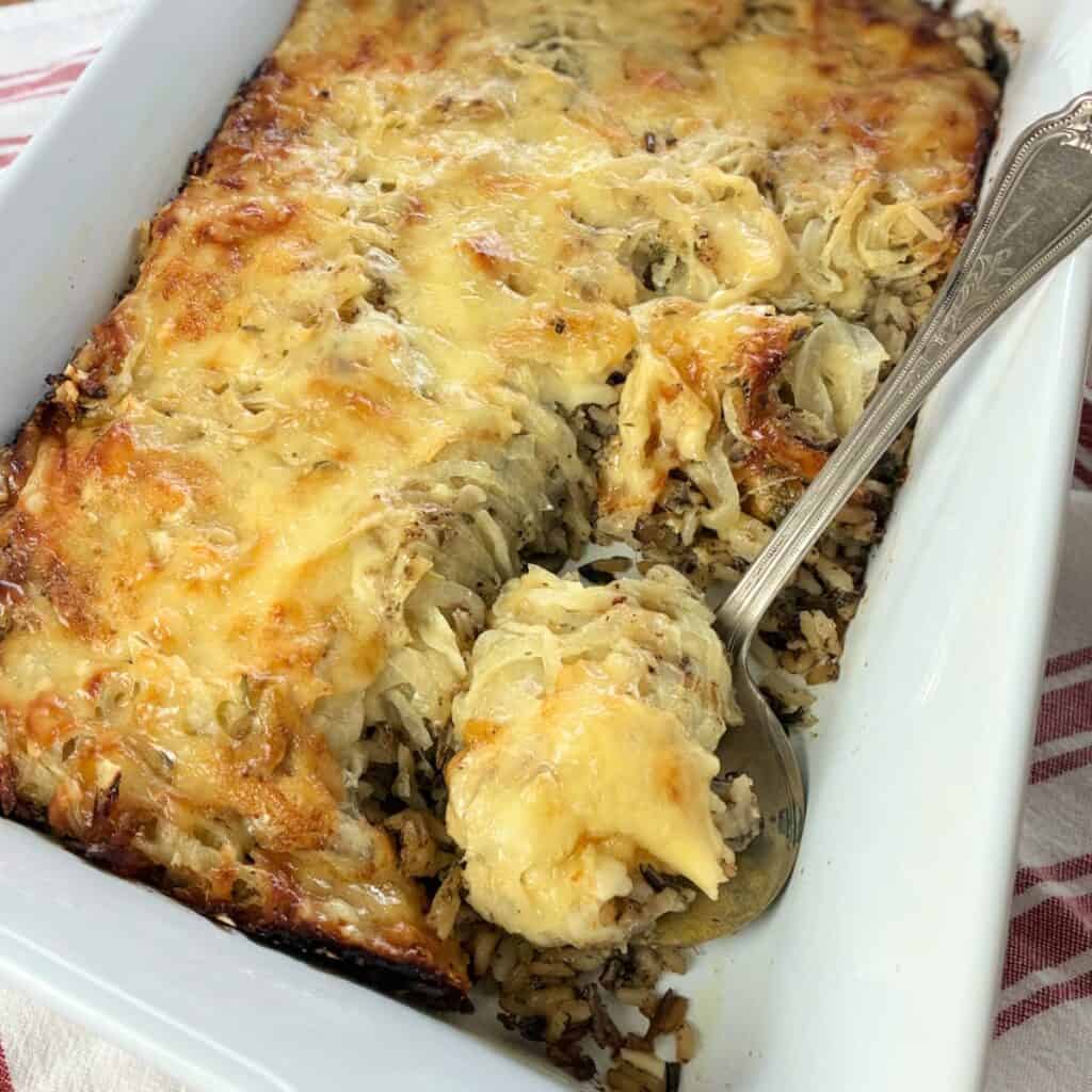 Wild Rice Mushroom Casserole on serving spoon in casserole dish.